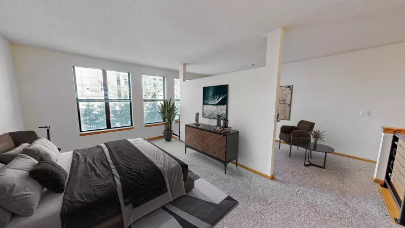 Modern bedroom with large windows, dark brown bed, TV console, and glimpse of an armchair.