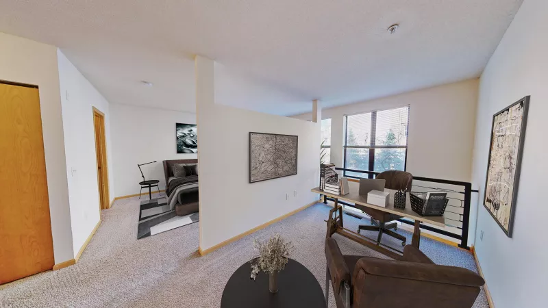 Modern apartment interior with a bedroom, a home office area with a desk, and a living space with brown leather armchairs.