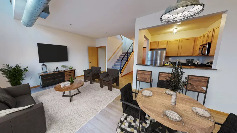 Spacious open-plan apartment featuring a living room, dining area, and kitchen with modern decor and exposed ductwork.