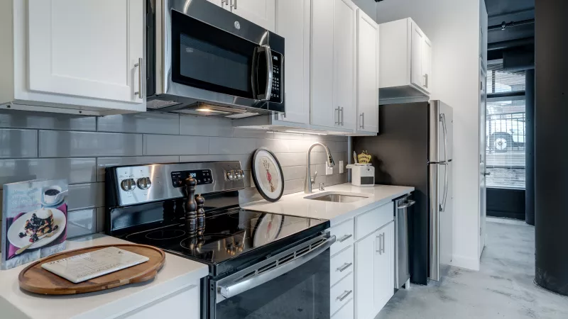 Modern kitchen with white cabinets, stainless steel appliances, and a gray subway tile backsplash.