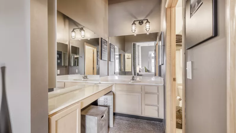 Stylish bathroom featuring a double vanity with two sinks, light countertops, large mirrors, and neutral walls.