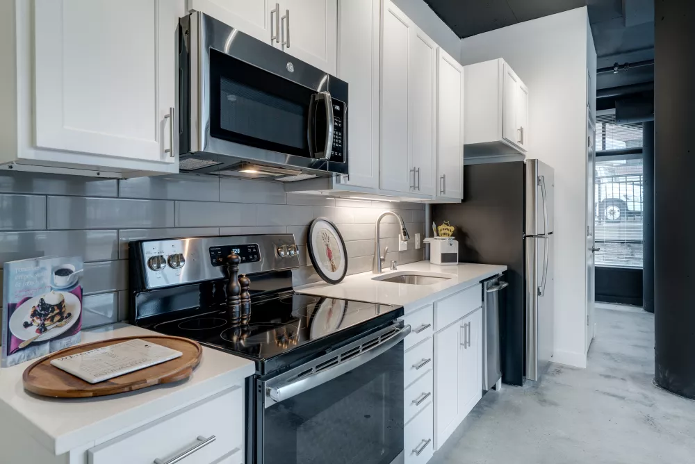 Modern kitchen with white cabinets, stainless steel appliances, and a gray subway tile backsplash.